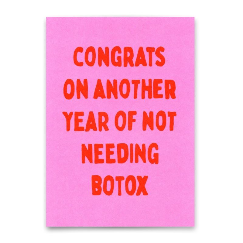 Postkarte mit rotem Schriftzug "Congrats on another year of not needing Botox" auf pinkem Hintergrund