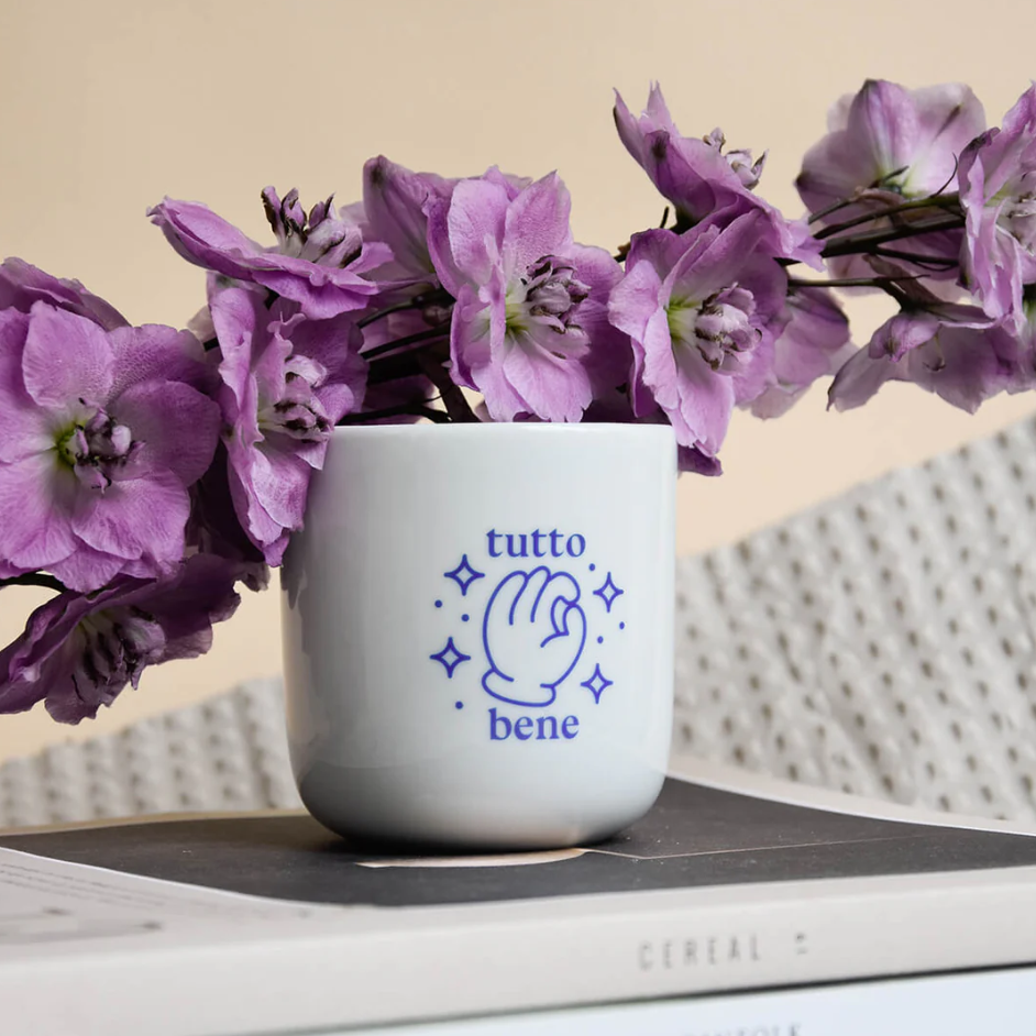 Porzellanbecher Tutto Bene von Studio Ciao mit blauem Handzeichen-Motiv und Schriftzug "tutto bene", umgeben von Sternen. Erhältlich im Shop "die Halle" bei Frau Rabe.
