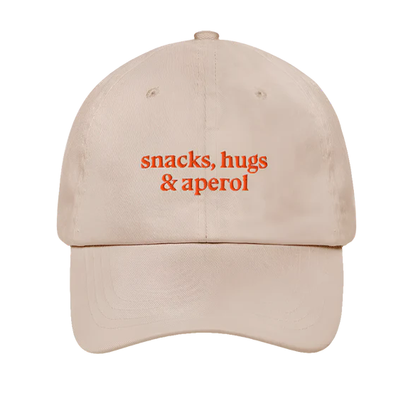 Cap mit gebogenem Schirm und Schriftzug „snacks, hugs & aperol“ in orange auf beigem Baumwollstoff, Studio Ciao